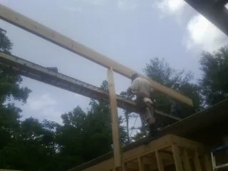Carpenter setting a ridge beam over a new addition frame — Ice Dam Removal by Roofing Brothers in Bath Springs