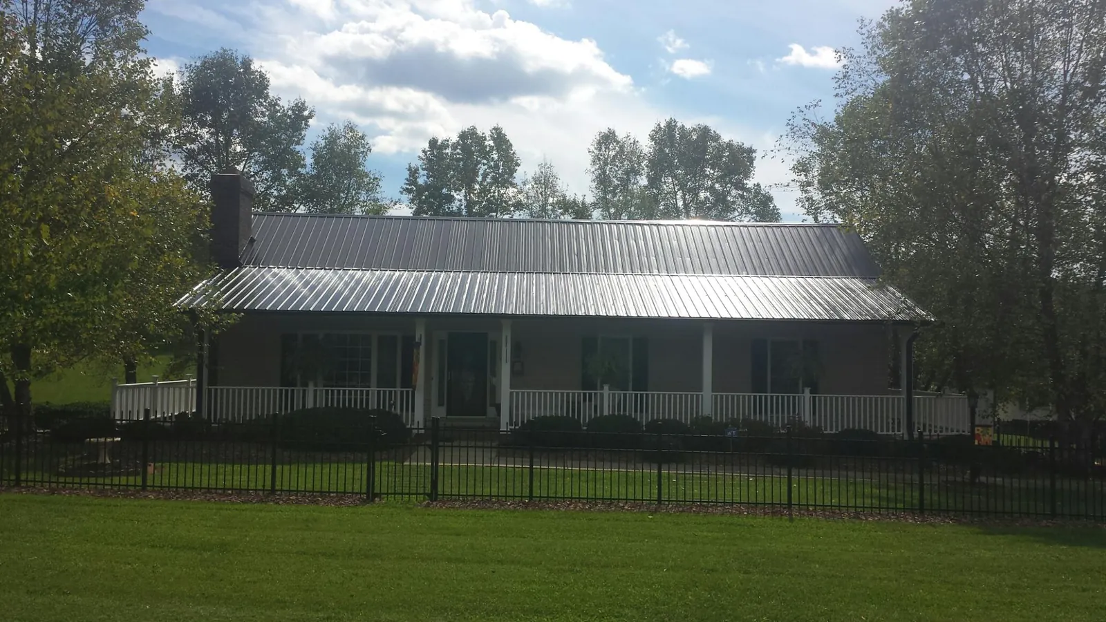 Gray metal roof on a brick ranch with a full width front porch — Gutter Guard Installation work by our crew in Bath Springs