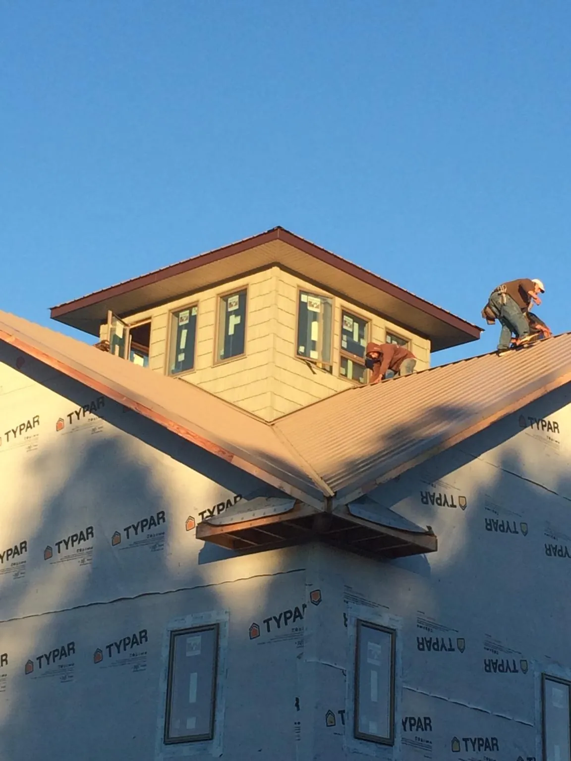 Roofers working around a rooftop cupola on a new metal roof at sunset — Roof Waterproofing in Bath Springs by Roofing Brothers